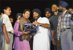 Sukhbir Badal, acting president of SAD (B), honours Punjabi singer Gurdas Mann on the concluding ceremony of the 22nd Baba Sheikh Farid Aagman Purb Mela at Faridkot on Sunday night. V. K. Meena, deputy commissioner, is also seen in the picture.