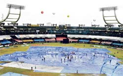 Groundstaff remove the accumulated rainwater from the pitch cover at the Jawaharlal Nehru stadium at Kochi