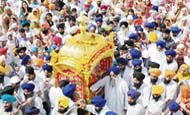 Devotees carry a golden palanquin with Guru Granth Sahib at a procession on the eve of the birth anniversary of Guru Ram Das in the Golden Temple in Amritsar