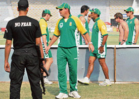 A Pakistan police commando stands guard next to South African cricketers during a practice session at the Gaddafi Stadium in Lahore on Friday.