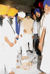 An ardent SAD activist, Jarnail Sekhon, puts on shoes in the presence of Chief Minister Parkash Singh Badal at Ghunus village in Bathinda on Sunday