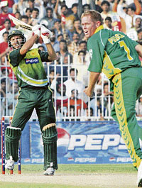 Shahid Afridi plays a shot as Shaun Pollock looks on during the third one-day international match.