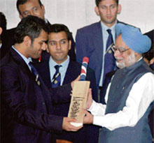 Cricket captain Mahendra Singh Dhoni presents a bat, autographed by T-20 team members, to Prime Minister Manmohan Singh in New Delhi on Tuesday.