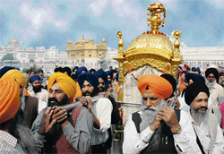 Devotees carry a golden palanquin having Guru Granth Sahib during a religious procession on the eve of the birth anniversary of Guru Nanak Dev in Amritsar