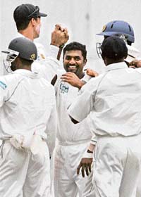 Sri Lankan bowler Muttiah Muralitharan (centre) celebrates as he equals the world record for most wickets in Test cricket after dismissing England batsman Ravi Bopara on the second day of the first Test between Sri Lanka and England in Kandy, Sri Lanka, on Sunday. Muralitharan equalled the world record of 708 wickets held by retired Australian leg spinner Shane Warne as he took four wickets and led his team's fightback.