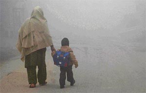 A woman takes a child to school in Amritsar on a foggy Wednesday morning.
