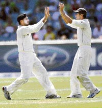 Harbhajan Singh (L) celebrates with Rahul Dravid after taking the wicket of Ricky Ponting during the third day of the first Test at the Melbourne Cricket Ground on Friday.