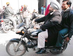 Bharat Inder Singh Chahal, with a friend on the pillion, drives a motorcycle in the streets of Patiala