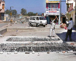 Municipal council workers break the RCC cover over a drain to relay it.