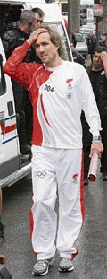 French ex-tennis player Arnaud Di Pasquale reacts as he carries the extinguished Olympic Torch in Paris on Monday.