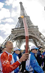 French athlete Stephane Diagana runs with the Olympic torch under tight police security at the Eiffel Tower in Paris on Monday.