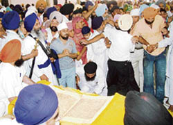 Devotees scramble to have a glimpse of handwritten Guru Granth Sahib as the Guru Manyo Granth Yatra reaches the Golden Temple in Amritsar