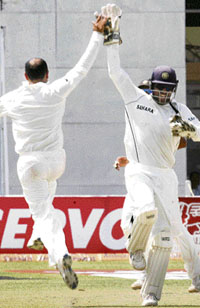 Virendra Sehwag (L) celebrates with Mahendra Singh Dhoni after taking the wicket of Graeme Smith during the final Test in Kanpur.
