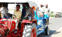 Migrant labourers on the move with a thresher in the wheat growing areas of Barnala district on Monday.