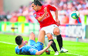 Manchester United�s Argentinian forward Carlos T�vez (R) is tackled by Wigan Athletic's Austrian midfielder Paul Scharner during their English Premier League match at the JJB Stadium in Wigan on Sunday. 