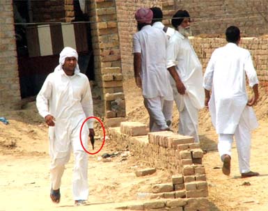 A SAD activist (above) armed with a revolver intimidates Congress supporters at a polling booth in Lambi village