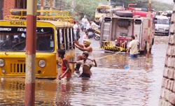 A school bus trapped in rain water being pulled out by a fire tender from the railway under-bridge in Moga