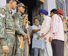 Jawans of the Central Reserve Police Force keep a watch, while a polling officer comes out with an electronic voting machine in Amritsar on Wednesday. 