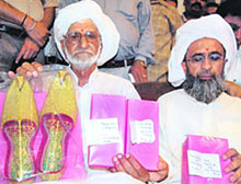 Dr Manmohan Singh�s childhood friend Raja Mohammed Ali (left), accompanied by his relative Mehmood Ahmed, shows the �jootis� and other gifts he has brought from Pakistan, on his arrival in Amritsar on Friday.