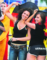 German supporters use their national flag to protect themselves against the rain as they watch the quarterfinal match between Germany and Portugal in Basel, during a public viewing session on Thursday.