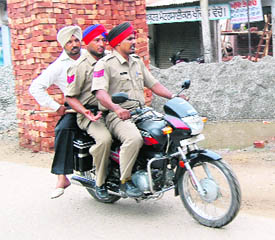 Three policemen on a motorbike drive down a road in Majitha (Amritsar) in violation of traffic rules.