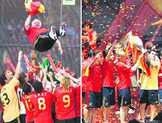 Players of the Spanish national soccer team lift coach Luis Aragones in the air during a homecoming event in Madrid on Monday. Players hold up the Euro 2008 trophy as they celebrate their victory on a stage at Madrid's Colon square on Monday.