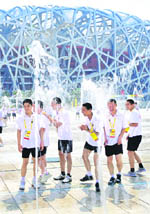 Students cool off at a public fountain on a hot summer day in front of the National Stadium. 