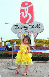 A young Chinese girl poses in front of a giant Olympics logo recently unveiled in Tiananmen Square in Beijing 