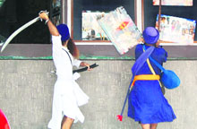 Sikh activists brandish swords and sticks outside a cinema hall screening the film, �Singh is Kinng,� in Amritsar on Friday.