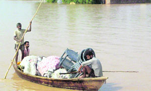 People take out their household items on boats from flood-hit Sanghera village in Moga district on Saturday.
