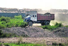 A truck unloads industrial ash on the Wagah road where foodgrains are stacked. A Tribune photograph