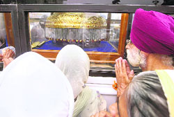 Devotees pay obeisance to the golden canopy made with 12 kg of gold for the Guru Granth Sahib’s palanquin in Amritsar on Saturday. It is to be presented to Takht Hazoor Sahib to mark the 300th Gurta Gurgaddi Diwas.