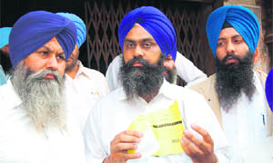 Baldev Singh (centre) shows torn nomination paper outside Cooperative Bank in Amritsar on Wednesday.