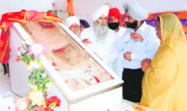 Sukhdev Singh Bedi, one of the 16th generation descendants of Guru Nanak Dev, shows the clothes (Chola Sahib) of the Guru to devotees at Dera Baba Nanak.