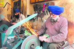 Members of the Siklighar community sharpen knives. 