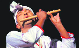 An artiste plays the flute in a play staged during Uttarakhand Mahotsav at Dehradun.