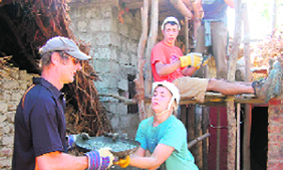 Students lay the roof of a house.