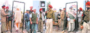 Punjab policemen can be seen relaxing and people passing through the metal detector without any check and (right) later, the cops frisk people as their superior arrives during the Shaheedi Jor Mela at Chamkaur Sahib