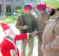 A boy dressed as Santa Claus distributes sweets among cops in Amritsar on Sunday.