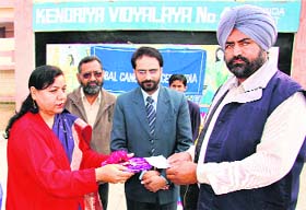 Senior general manager of the Global Cancer Concern (India) and Principal of KV No. 4 hand over money to Joginder Singh as a help to his cancer-affected children in Bathinda