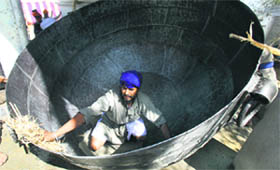 a devotee cleans a huge iron cauldron