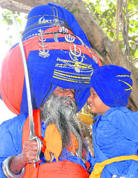 Major Singh, a Nihang wearing a 430-metre-long turban, talks to a young Nihang