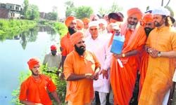 Baba Balbir Singh Seechewal shows water sample of Kala Sanghian drain in Jalandhar on Wednesday. Mohinder Singh Kaypee and Hans Raj Hans are also seen in the picture
