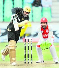 Chris Gayle of Kolkata Knight Riders hits the ball towards the boundary as Sri Lankan wicketkeeper Kumar Sangakkara of The King's XI Punjab looks on