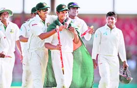 Mahmudullah (C) is adorned with a national flag by his teammates following their victory at the end of the final day of the first Test match
