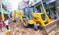 Municipal corporation employees dig a road in Raghunath Bazaar in Jammu for laying sewer pipes