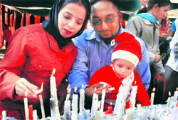 A family lights candles in a church on the powerhouse road in Bathinda on Christmas Day