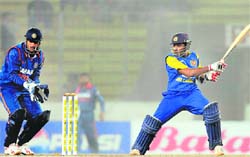Sri Lankan cricketer Mahela Jayawardene (R) plays a shot as the Indian captain Mahendra Singh Dhoni looks on in Dhaka