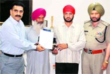 Police Commissioner Varinder Kumar (left) honours two residents of Bal Kallan village in Amritsar on Saturday. A Tribune photograph