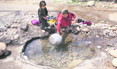 A woman fills a pitcher from accumulated water owing to a leakage on Bhatindi 